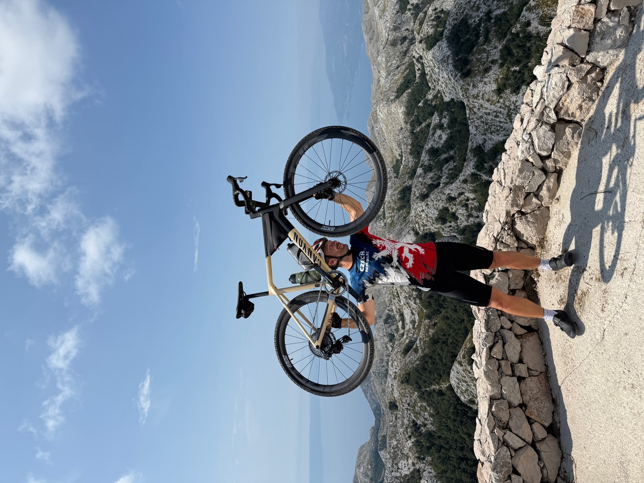 Ein Radfahrer hält ein Fahrrad an einem Aussichtspunkt über einer bergigen Landschaft